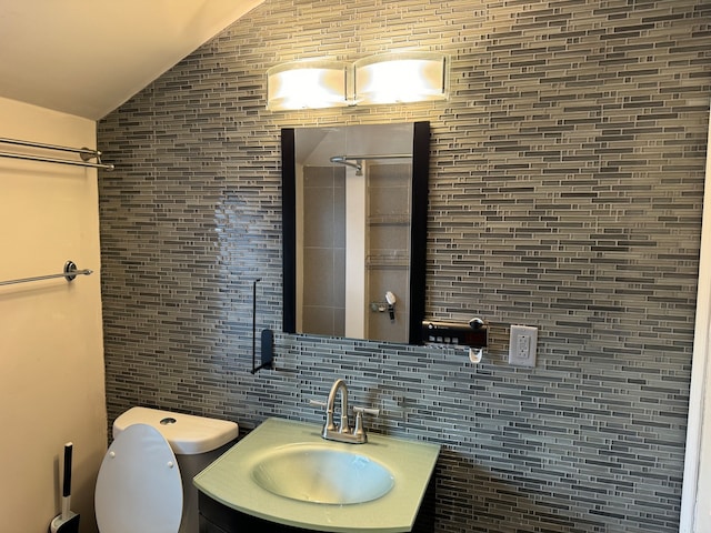 bathroom featuring lofted ceiling, toilet, tile walls, tasteful backsplash, and vanity