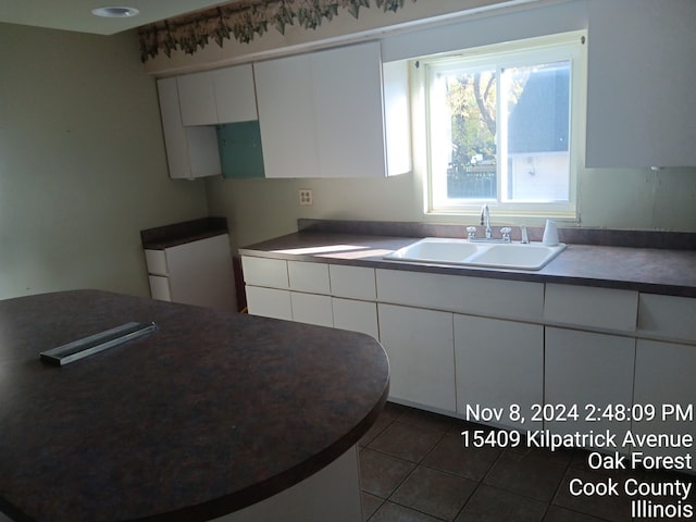 kitchen featuring white cabinets, refrigerator, dark tile patterned floors, and sink