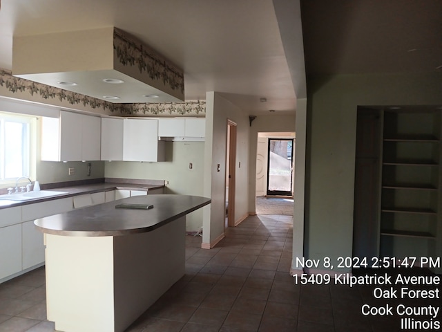 kitchen featuring tile patterned floors, white cabinetry, sink, and a kitchen island