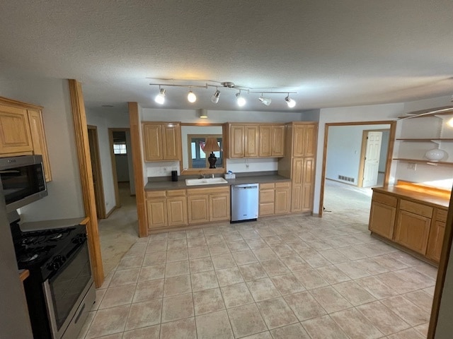 kitchen with light tile patterned flooring, a textured ceiling, stainless steel appliances, and sink