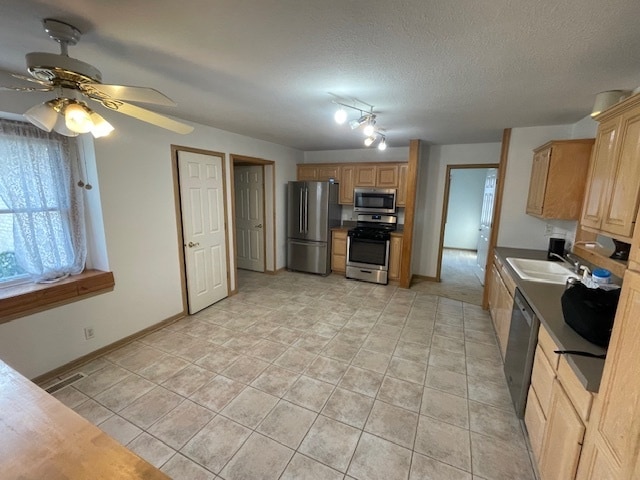 kitchen with a textured ceiling, stainless steel appliances, ceiling fan, sink, and light tile patterned floors