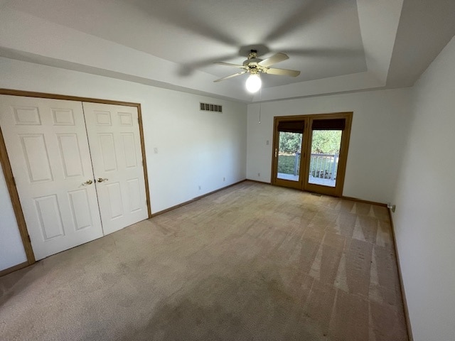 unfurnished bedroom featuring light carpet, french doors, a closet, and ceiling fan