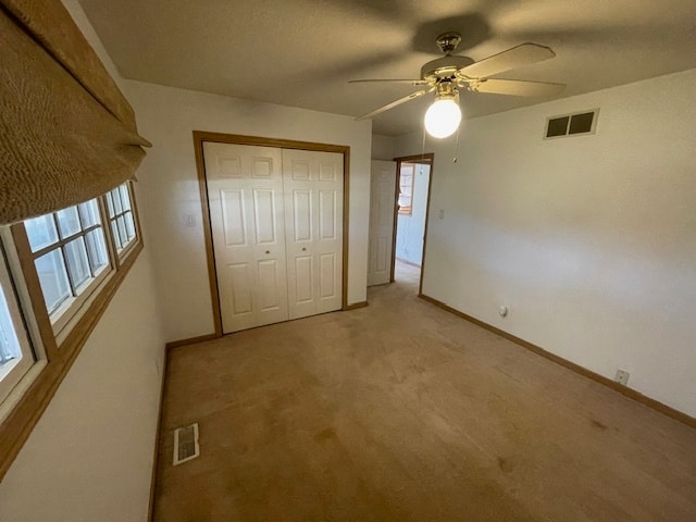 unfurnished bedroom with ceiling fan, a closet, and light carpet