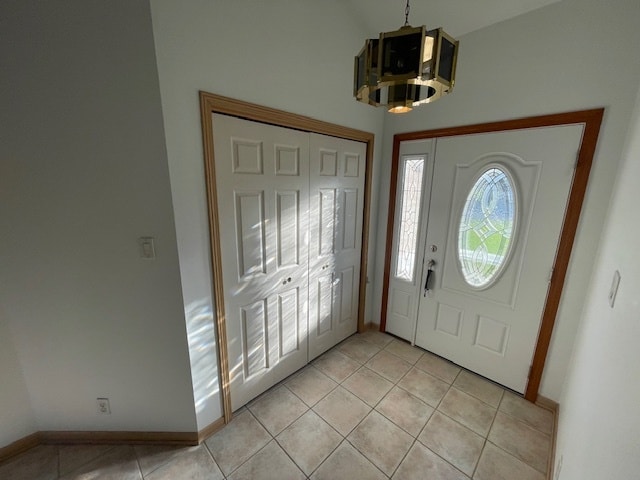 tiled foyer entrance with a chandelier