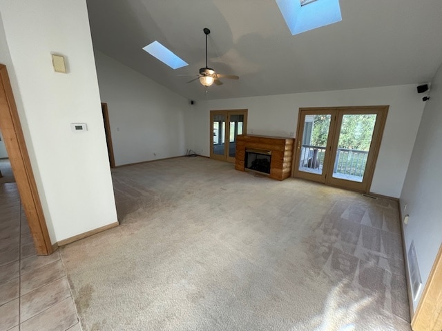 unfurnished living room featuring a skylight, ceiling fan, high vaulted ceiling, and light carpet