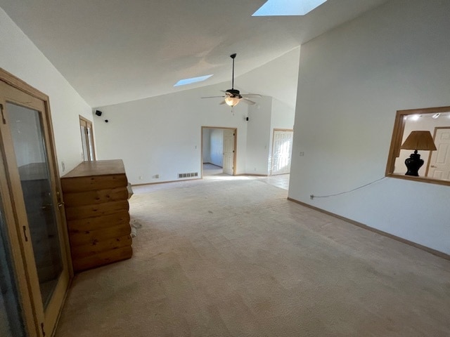 unfurnished living room with ceiling fan, light carpet, high vaulted ceiling, and a skylight