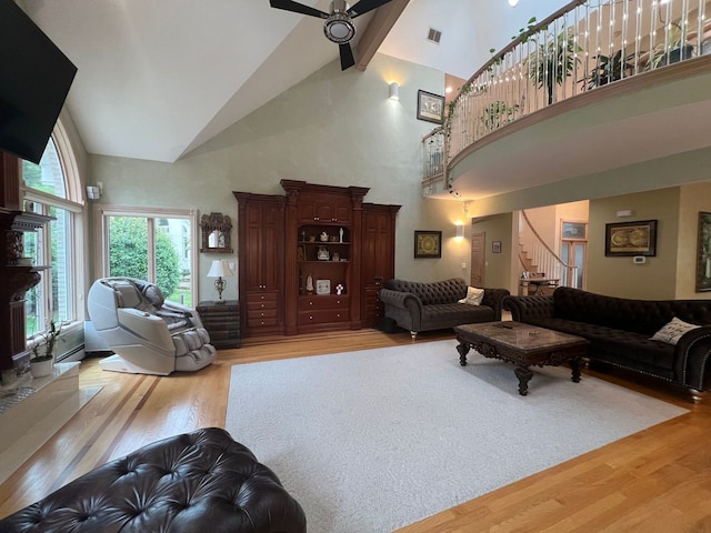 living room with light hardwood / wood-style floors, ceiling fan, and high vaulted ceiling