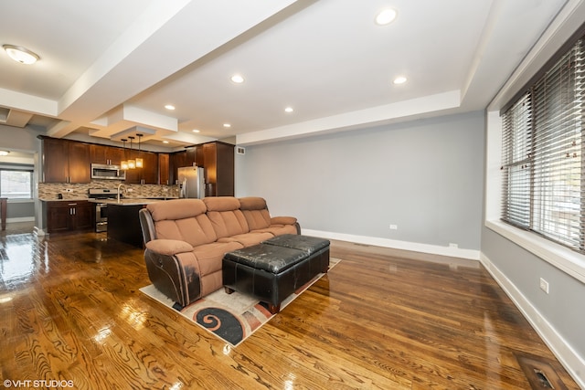 living room with dark hardwood / wood-style flooring, beamed ceiling, and sink