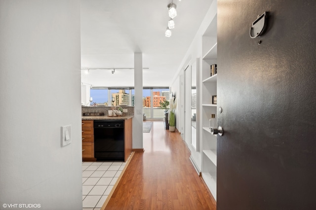 hallway featuring light wood-type flooring, floor to ceiling windows, and rail lighting