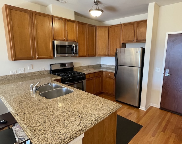 kitchen with kitchen peninsula, sink, light wood-type flooring, and appliances with stainless steel finishes