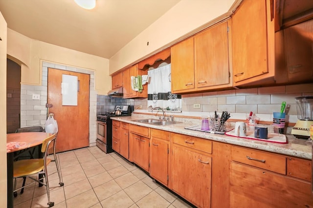 kitchen with decorative backsplash, stainless steel range with gas cooktop, sink, and light tile patterned flooring