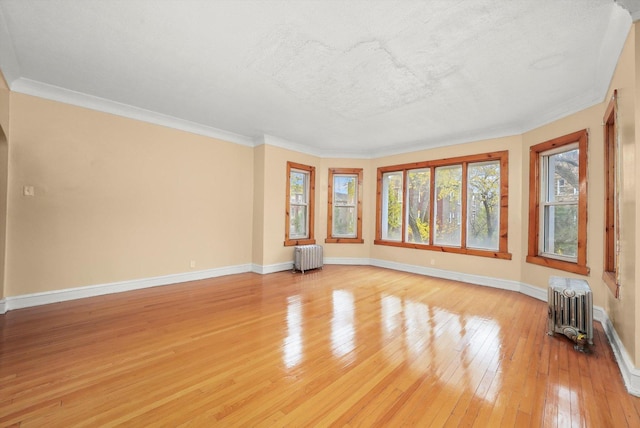 unfurnished room featuring radiator heating unit, light hardwood / wood-style floors, and ornamental molding