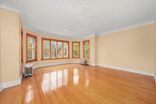 empty room featuring basketball hoop, ornamental molding, and radiator