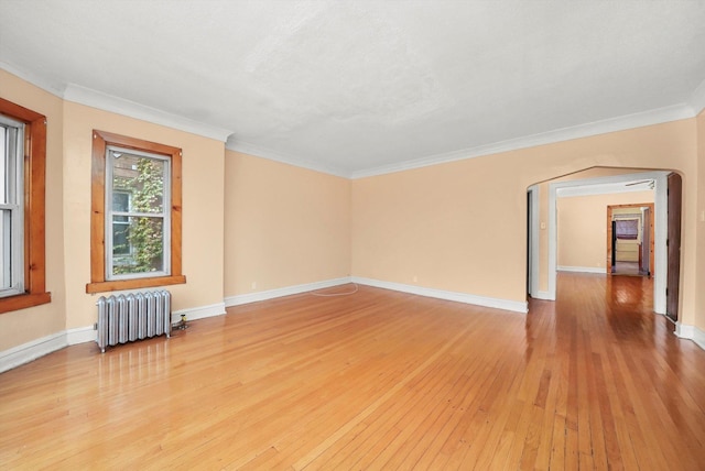 spare room featuring light wood-type flooring, radiator heating unit, and crown molding