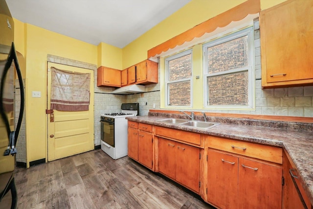 kitchen with sink, dark wood-type flooring, backsplash, refrigerator, and white gas range oven