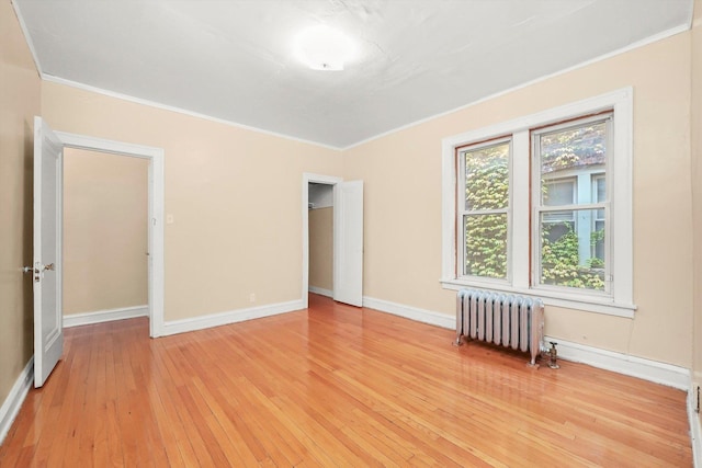 spare room with radiator heating unit, light wood-type flooring, and crown molding