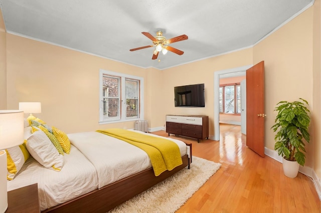 bedroom featuring radiator, ceiling fan, crown molding, and light hardwood / wood-style floors