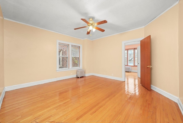 empty room with ceiling fan, radiator heating unit, light hardwood / wood-style flooring, and ornamental molding