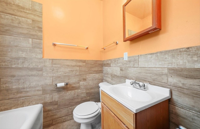 bathroom featuring vanity, toilet, tile walls, and a washtub