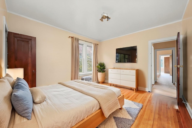 bedroom with light wood-type flooring, radiator heating unit, and crown molding