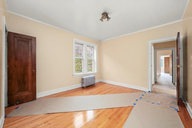 unfurnished room featuring radiator heating unit, hardwood / wood-style flooring, and crown molding