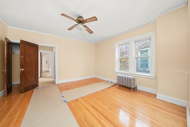 empty room with ceiling fan, radiator heating unit, and light hardwood / wood-style flooring