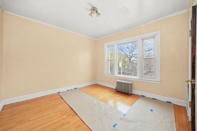 spare room with hardwood / wood-style floors, crown molding, and radiator