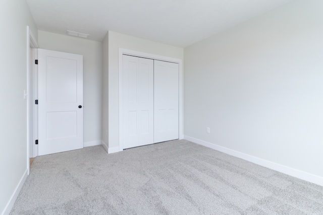 unfurnished bedroom featuring light colored carpet and a closet