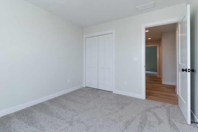 unfurnished bedroom with light colored carpet and a closet