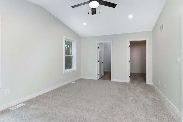 unfurnished bedroom with a spacious closet, vaulted ceiling, ceiling fan, and ensuite bath