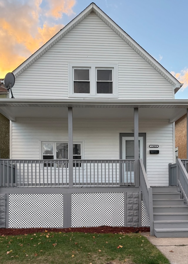 back house at dusk featuring covered porch