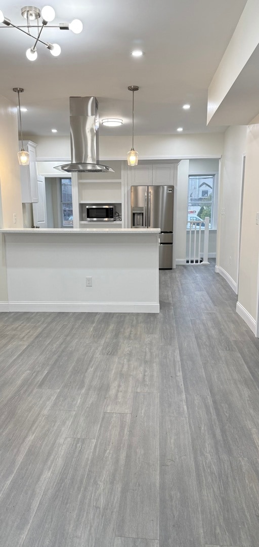 kitchen featuring white cabinetry, stainless steel appliances, wood-type flooring, and island exhaust hood