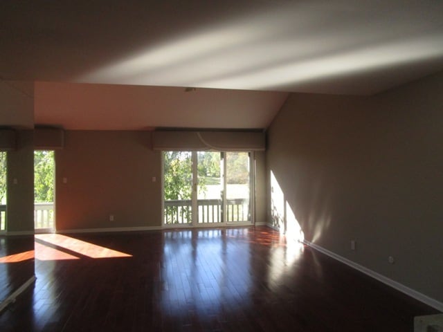 unfurnished room with hardwood / wood-style floors and vaulted ceiling