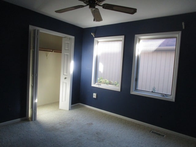 unfurnished bedroom with a closet, carpet, and ceiling fan