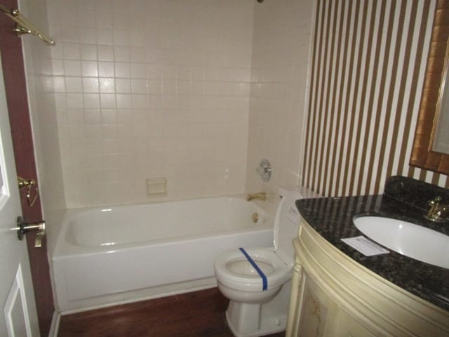 full bathroom featuring hardwood / wood-style floors, vanity, toilet, and tiled shower / bath combo