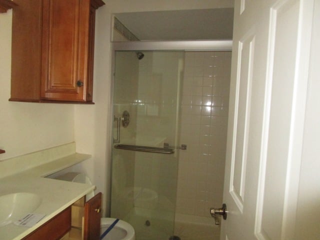 bathroom with walk in shower, vanity, and toilet