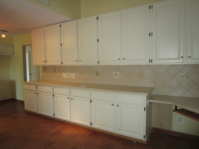 kitchen featuring dark wood-type flooring, white cabinetry, and backsplash