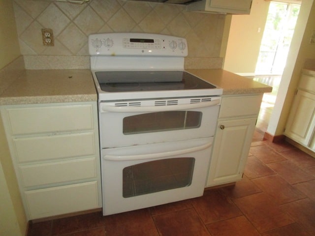 kitchen with tasteful backsplash, dark tile patterned floors, and white electric range