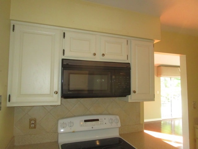 kitchen with white cabinets, white range oven, and backsplash