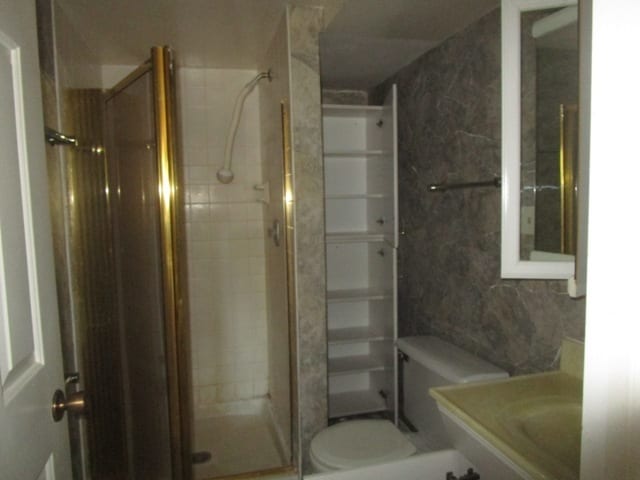 bathroom with backsplash, vanity, an enclosed shower, toilet, and tile walls