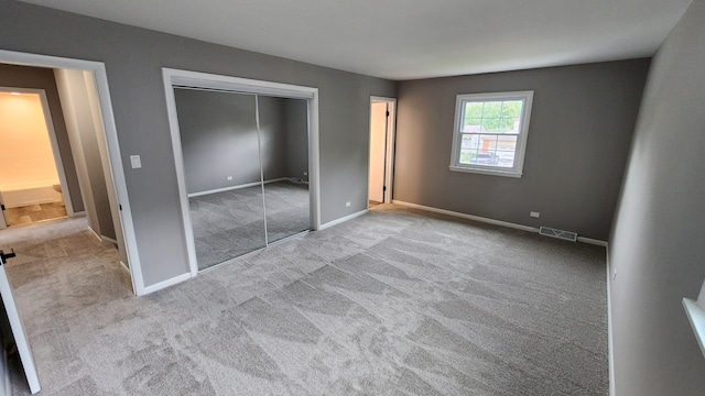 unfurnished bedroom with a closet and light colored carpet