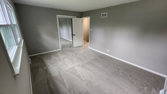 unfurnished bedroom with light colored carpet and a closet