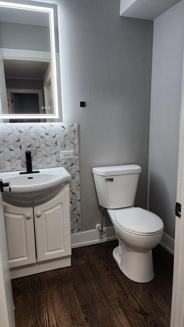 bathroom featuring wood finished floors, toilet, decorative backsplash, and baseboards