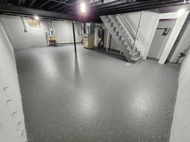 basement featuring water heater, heating unit, and stairway