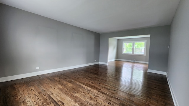 unfurnished room with dark wood-type flooring and baseboards