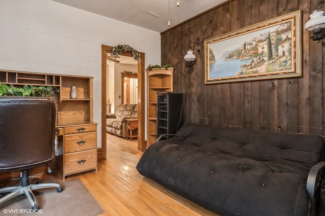 bedroom with wood walls and light hardwood / wood-style floors