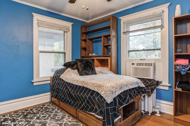 bedroom with ornamental molding, hardwood / wood-style floors, cooling unit, and ceiling fan