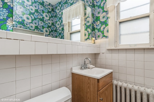 bathroom with tile walls, radiator heating unit, vanity, and toilet