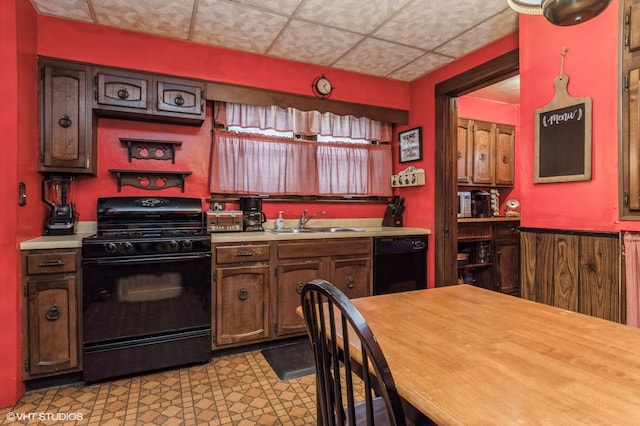 kitchen featuring wooden walls, sink, and black appliances