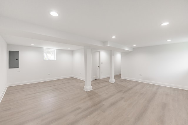 basement with light wood-type flooring and electric panel